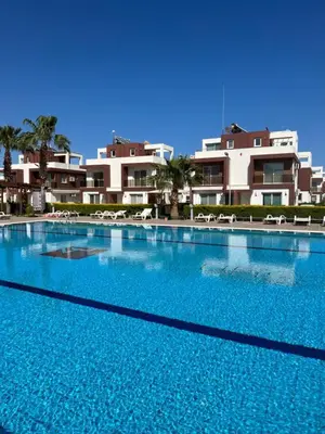 a large swimming pool with chairs and buildings in the background at Royal Sun Comfortable Villa in Larnaka