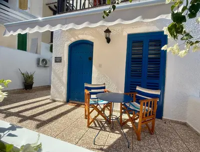 a table and chairs in front of a building with blue doors at Protaras Sol 2 Bedroom Holiday Let Apartment in Protaras