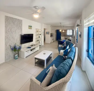 a living room with a blue couch and a table at Protaras Sol 2 Bedroom Holiday Let Apartment in Protaras