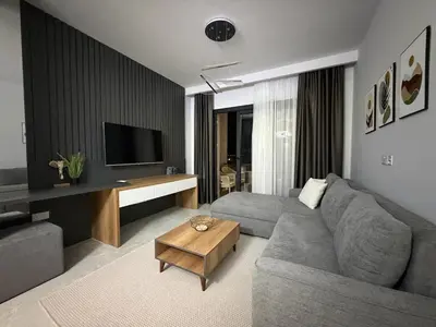 a living room with a gray couch and a television at Riverside Life residence in Long Beach, Iskele, North Cyprus in Dherinia