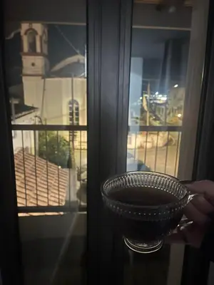 a person holding a bowl in front of a window at Το Αρχοντικόν in Ayvaryara