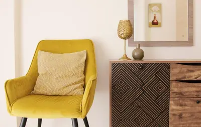 a yellow chair with a pillow next to a dresser at NISSI Elena BEACH apt in Ayia Napa