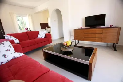 a living room with a red couch and a flat screen tv at The Love Nest in Pissouri