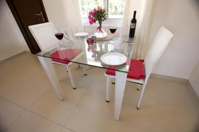 a glass table with two white chairs and wine glasses at The Love Nest in Pissouri