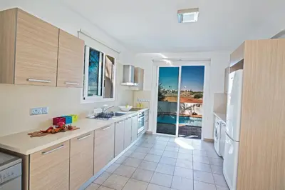 a kitchen with wooden cabinets and a view of the ocean at Seaspray in Protaras