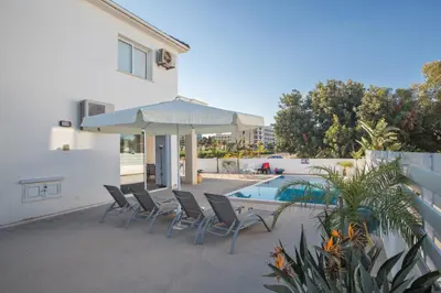 a patio with chairs and an umbrella next to a pool at Flouressia Villa 4 in Protaras