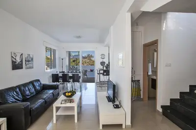 a living room with a black leather couch and a tv at Flouressia Villa 4 in Protaras