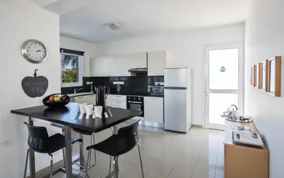 a kitchen with a black table and a white refrigerator at Flouressia Villa 4 in Protaras