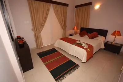 a bedroom with a bed with red pillows and a rug at Bay Villas in Pissouri