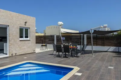 a patio with a table and chairs and a pool at Protaras Villa Hollywood in Protaras