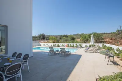 a patio with tables and chairs next to a swimming pool at Greco Villas in Protaras