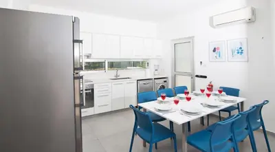 a dining room with a table and blue chairs at Greco Villas in Protaras