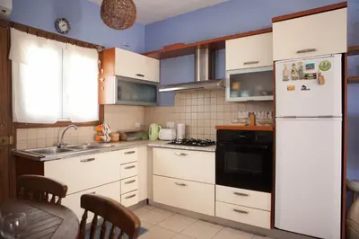 a kitchen with white cabinets and a white refrigerator at Aquarian Beachfront Apartment in Larnaka
