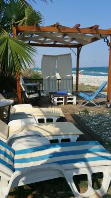a group of beds on a beach with a gazebo at Aquarian Beachfront Apartment in Larnaka