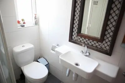 a bathroom with a toilet and a sink and a mirror at Aquarian Beachfront Apartment in Larnaka