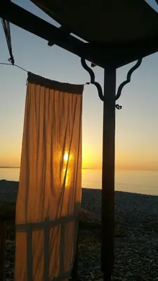 a curtain on the beach with the sunset in the background at Aquarian Beachfront Apartment in Larnaka