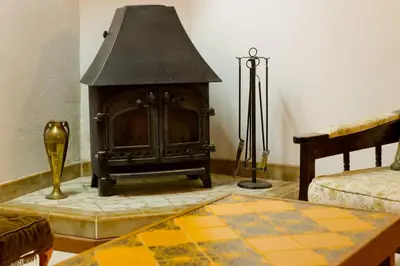 a living room with a wood stove in the corner at The Old Olive Mill House by TrulyCyprus in Doros