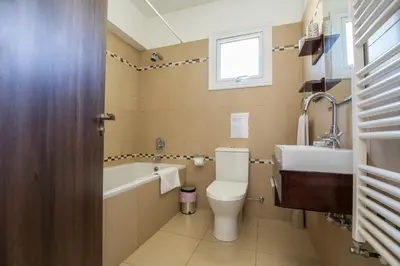 a bathroom with a toilet and a tub and a sink at Nancy Villas in Protaras