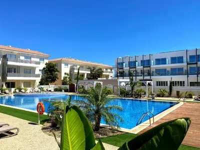 a swimming pool in front of a large building at Domino Blue Apartment in Paralimni