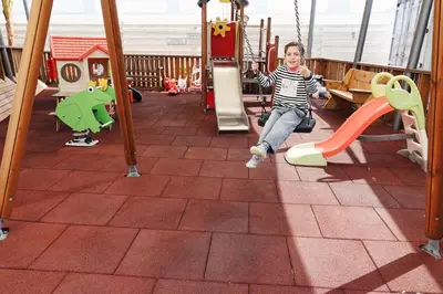 a young child sitting on a slide on a playground at Silver Sea Holiday Apartments in Ayia Napa