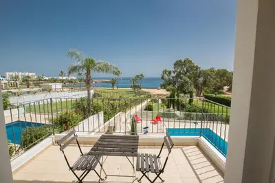 a balcony with two chairs and a table and a pool at Shaye Front Line Villa in Protaras