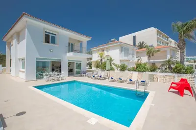 a villa with a swimming pool in front of a house at Shaye Front Line Villa in Protaras