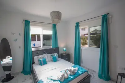 a bedroom with a bed with blue curtains and a window at Broadway Villas in Protaras