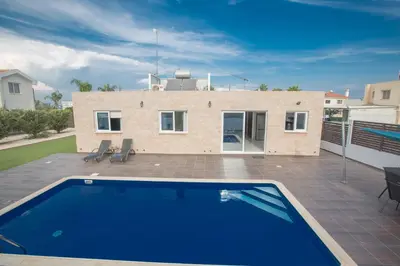 a villa with a swimming pool in front of a house at Broadway Villas in Protaras