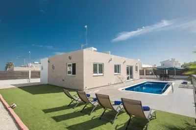 a house with a yard with chairs and a swimming pool at Broadway Villas in Protaras