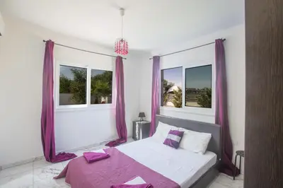 a bedroom with purple curtains and a bed with a purple blanket at Broadway Villas in Protaras