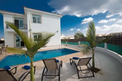 a villa with a swimming pool and two palm trees at Halle Villa in Protaras