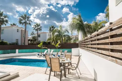a patio with a table and chairs next to a swimming pool at Halle Villa in Protaras