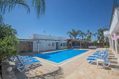a swimming pool with lounge chairs next to a building at Papas Family Villa in Paralimni