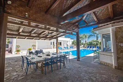 a patio with a table and chairs and a pool at Papas Family Villa in Paralimni