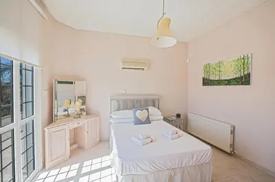 a white bedroom with two beds and a mirror at Papas Family Villa in Paralimni