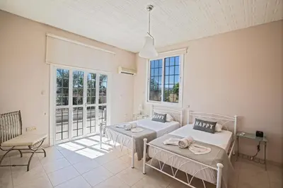 a bedroom with two beds and a large window at Papas Family Villa in Paralimni