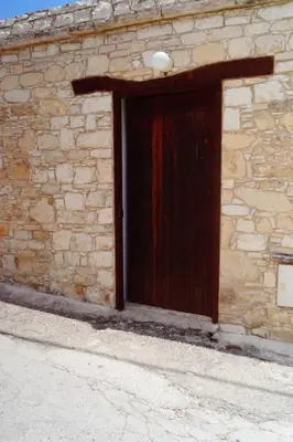a wooden door on a stone building with aphalt at Makrinari Tis Pano Geitonias in Salamiou