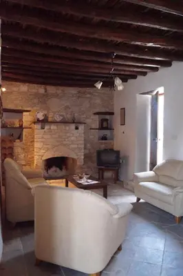 a living room with two chairs and a fireplace at Makrinari Tis Pano Geitonias in Salamiou