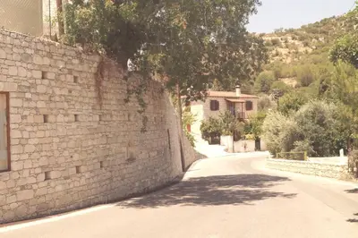 a stone wall with a tree on the side of a road at Makrinari Tis Pano Geitonias in Salamiou