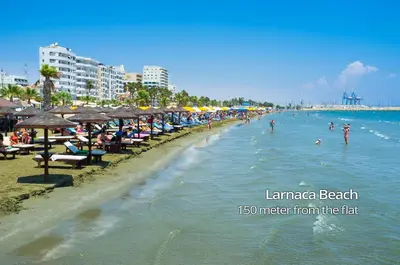 a beach with a bunch of people in the water at Paradise Palms Seaview Apartment in Larnaka