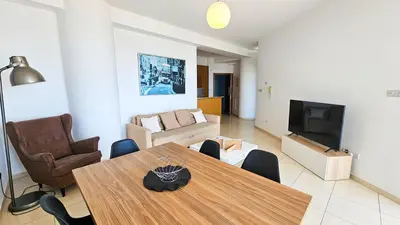 a living room with a table and a couch and a television at Paradise Palms Seaview Apartment in Larnaka