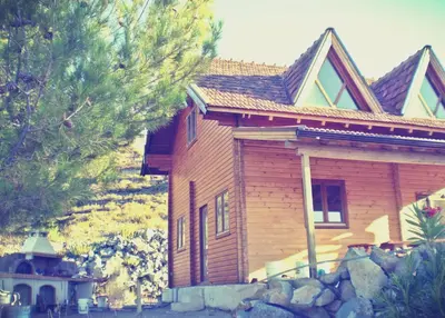 a wooden house with a stone wall in front of it at Agros Timber Log House in Agros