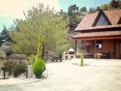 a building with a bench and a tree in front of it at Agros Timber Log House in Agros