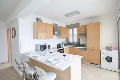 a kitchen with a counter with chairs and a dishwasher at Pallinio Fig Tree Bay Apartments in Protaras
