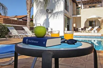 a table with a book and an apple and a glass of beer at Villa Regina in Ayia Napa
