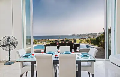 a dining room with a table and chairs and a view of the ocean at Leana Front Line Villa in Protaras