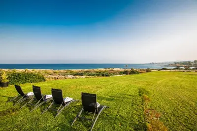 a group of chairs sitting in a field with the ocean at Leana Front Line Villa in Protaras