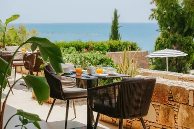 a table and chairs on a patio with a view of the ocean at Royal Apollonia by Louis Hotels in Limassol