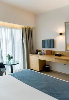 a hotel room with a bed and a tv and a table at Ajax Hotel in Limassol