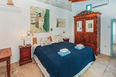 a bedroom with a bed with blue sheets and a wooden cabinet at Archondia House - Holiday Apartments With Pool in Kalavasos